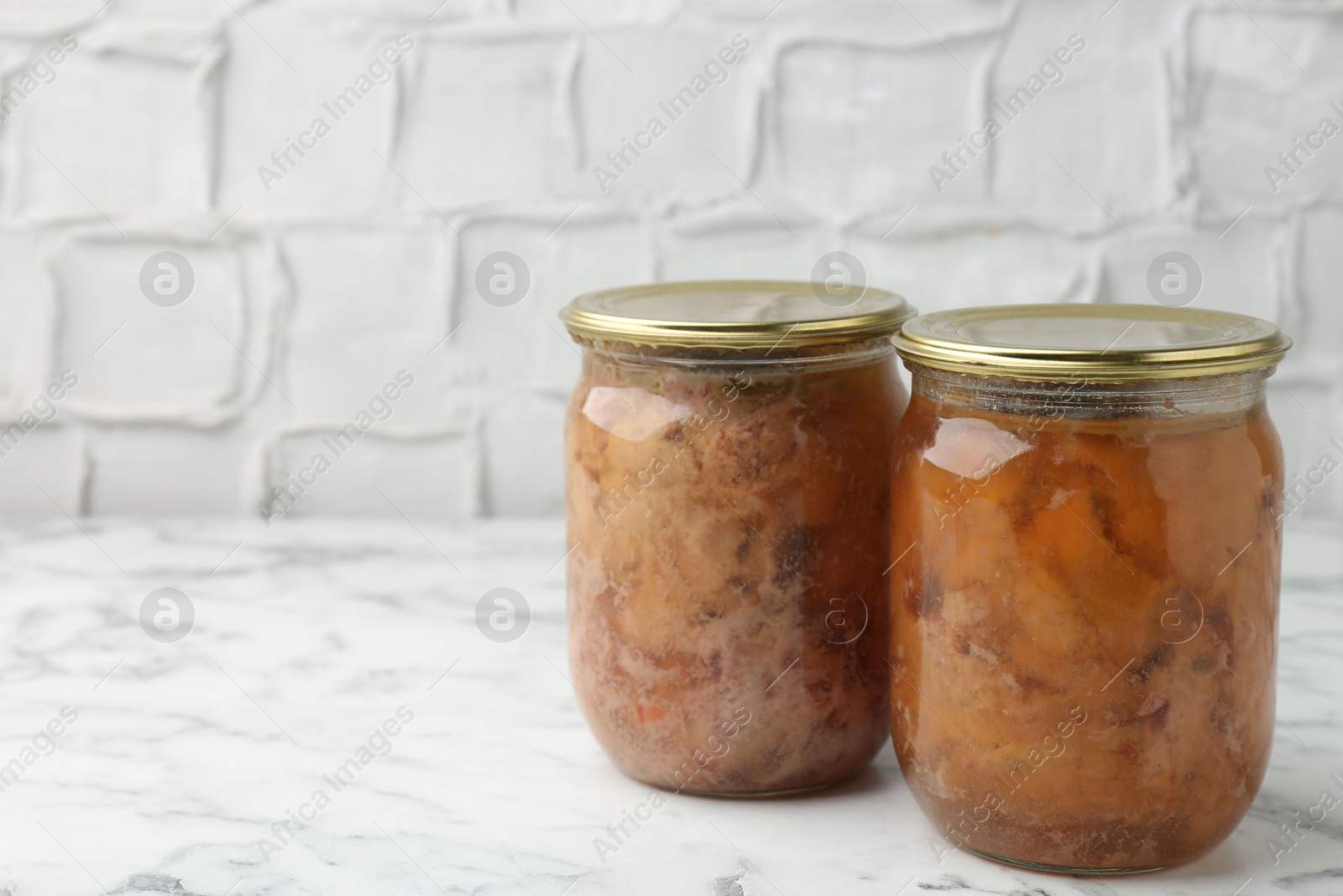 Photo of Canned meat in glass jar on white marble table, space for text