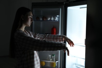 Photo of Young woman suffering from sleepwalking near fridge at home