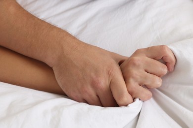 Lovely couple holding hands in bed, closeup