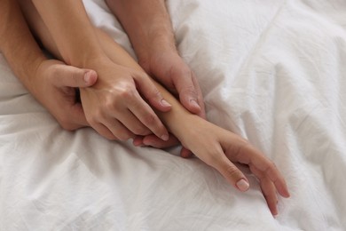 Photo of Lovely couple holding hands in bed, closeup