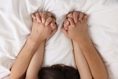 Photo of Lovely couple holding hands in bed, top view