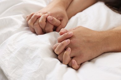 Photo of Lovely couple holding hands in bed, closeup