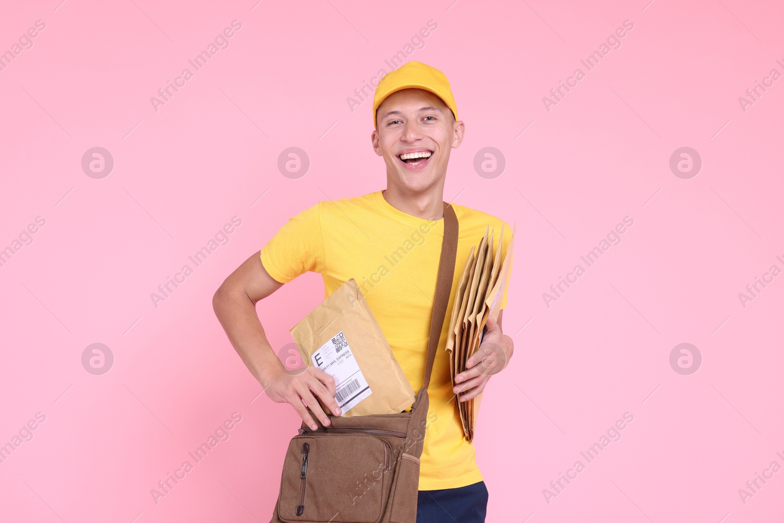 Photo of Happy postman with bag and envelopes on pink background