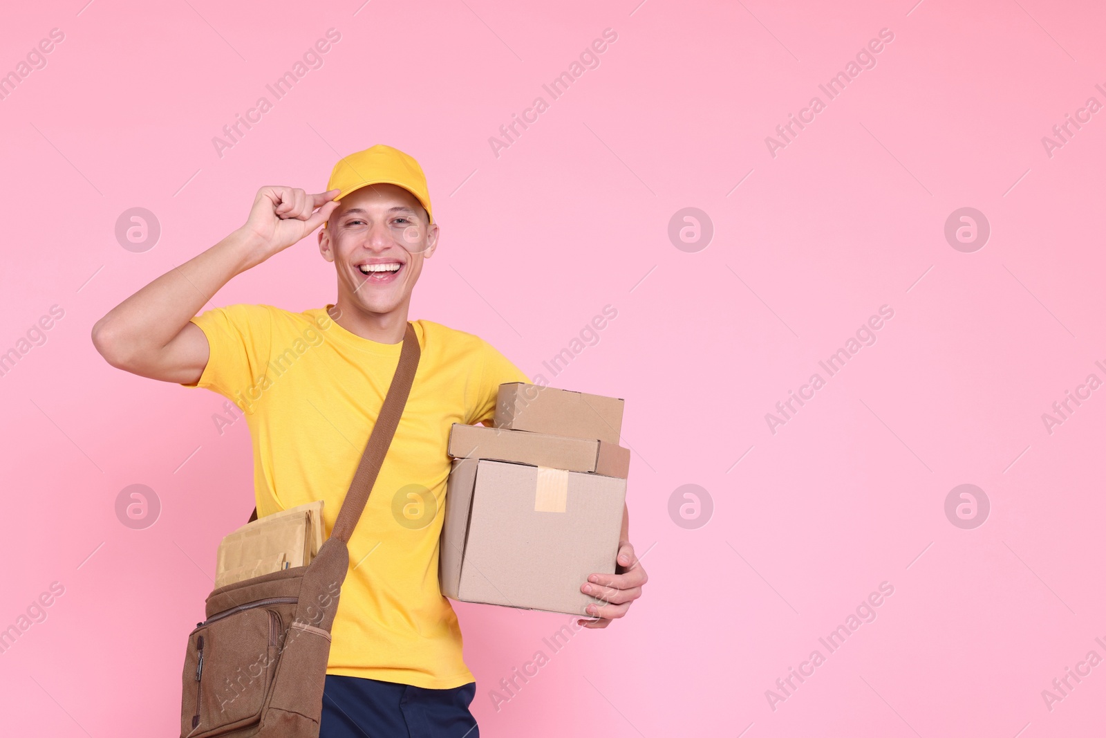 Photo of Happy postman with parcels on pink background. Space for text