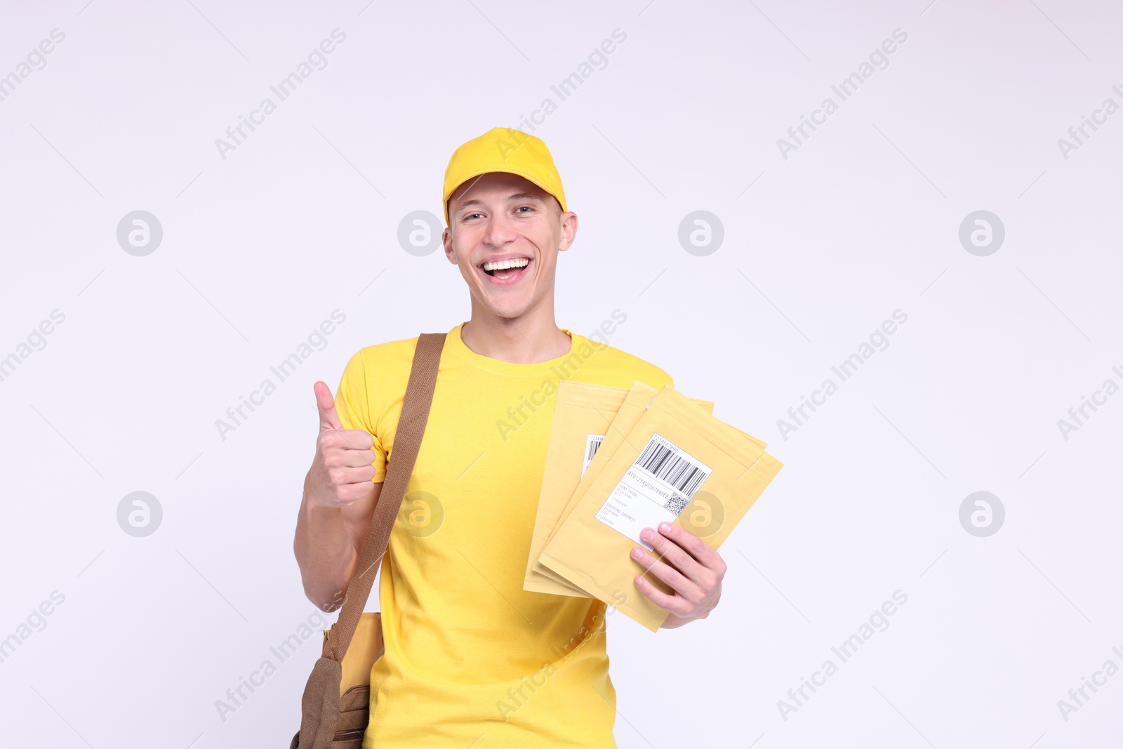 Photo of Happy postman with bag and envelopes showing thumbs up on white background