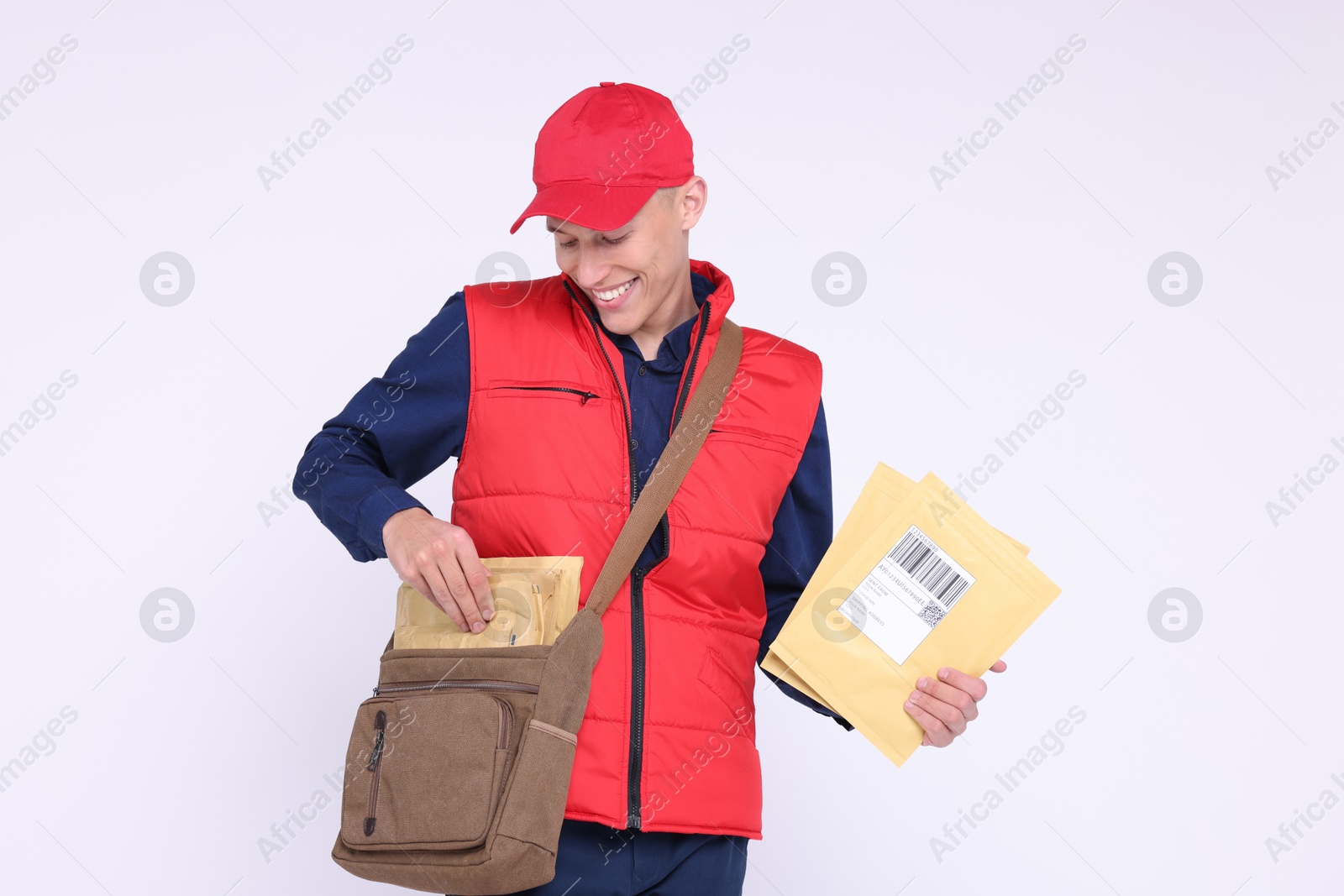 Photo of Happy postman with bag and envelopes on white background