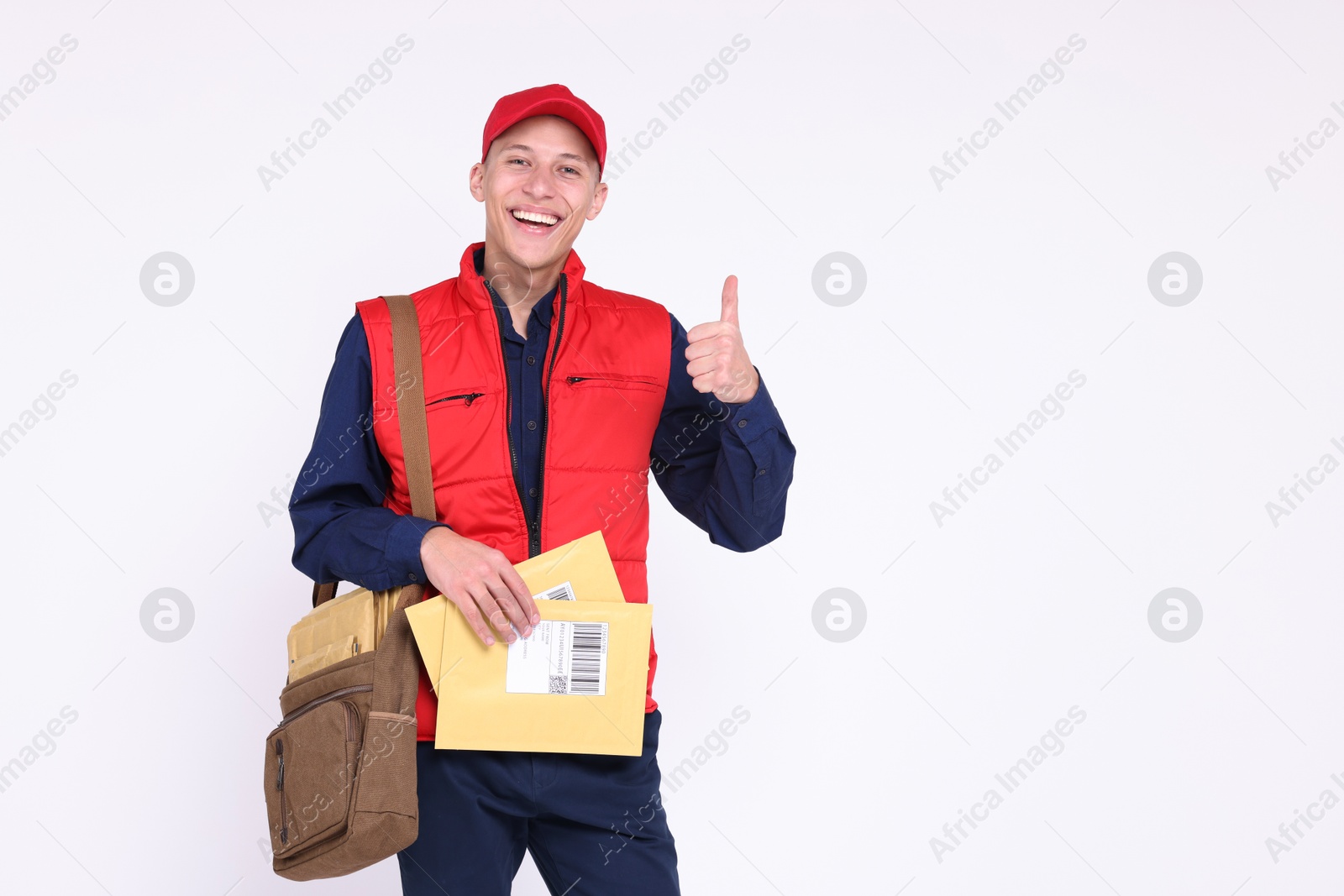 Photo of Happy postman with envelopes showing thumbs up on white background. Space for text