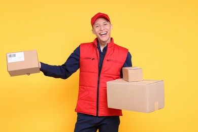 Photo of Happy postman with parcels on yellow background