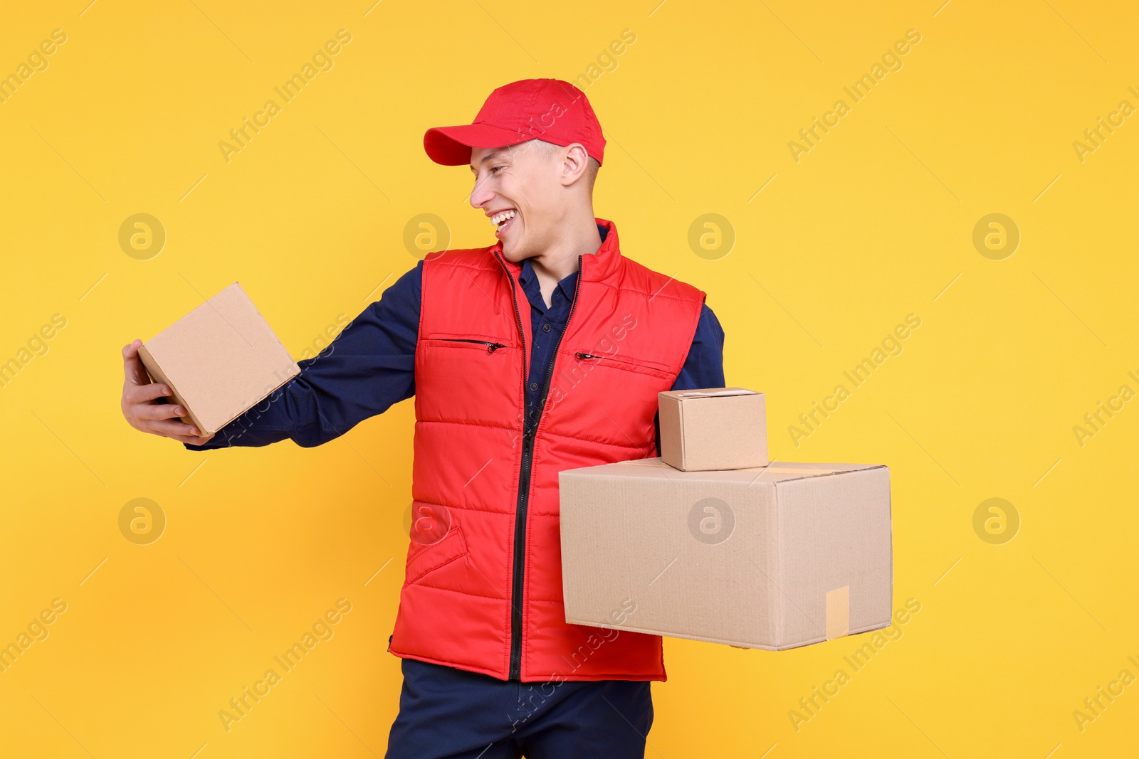 Photo of Happy postman with parcels on yellow background