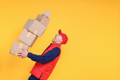 Photo of Emotional postman with parcels on yellow background. Space for text