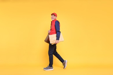 Photo of Happy postman with bag and envelopes on yellow background