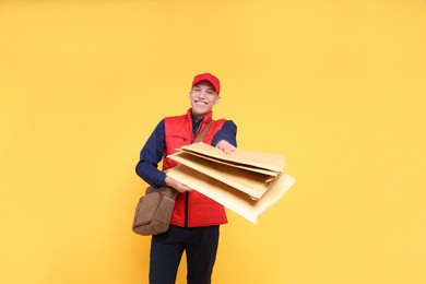 Photo of Happy postman with bag giving envelopes on yellow background