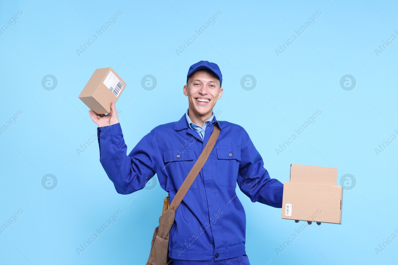 Photo of Happy postman with parcels on light blue background