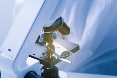 Photo of Scientist working with microscope in laboratory, closeup