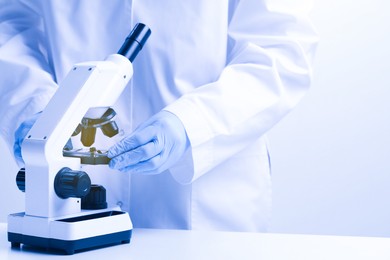 Photo of Scientist working with microscope in laboratory, closeup