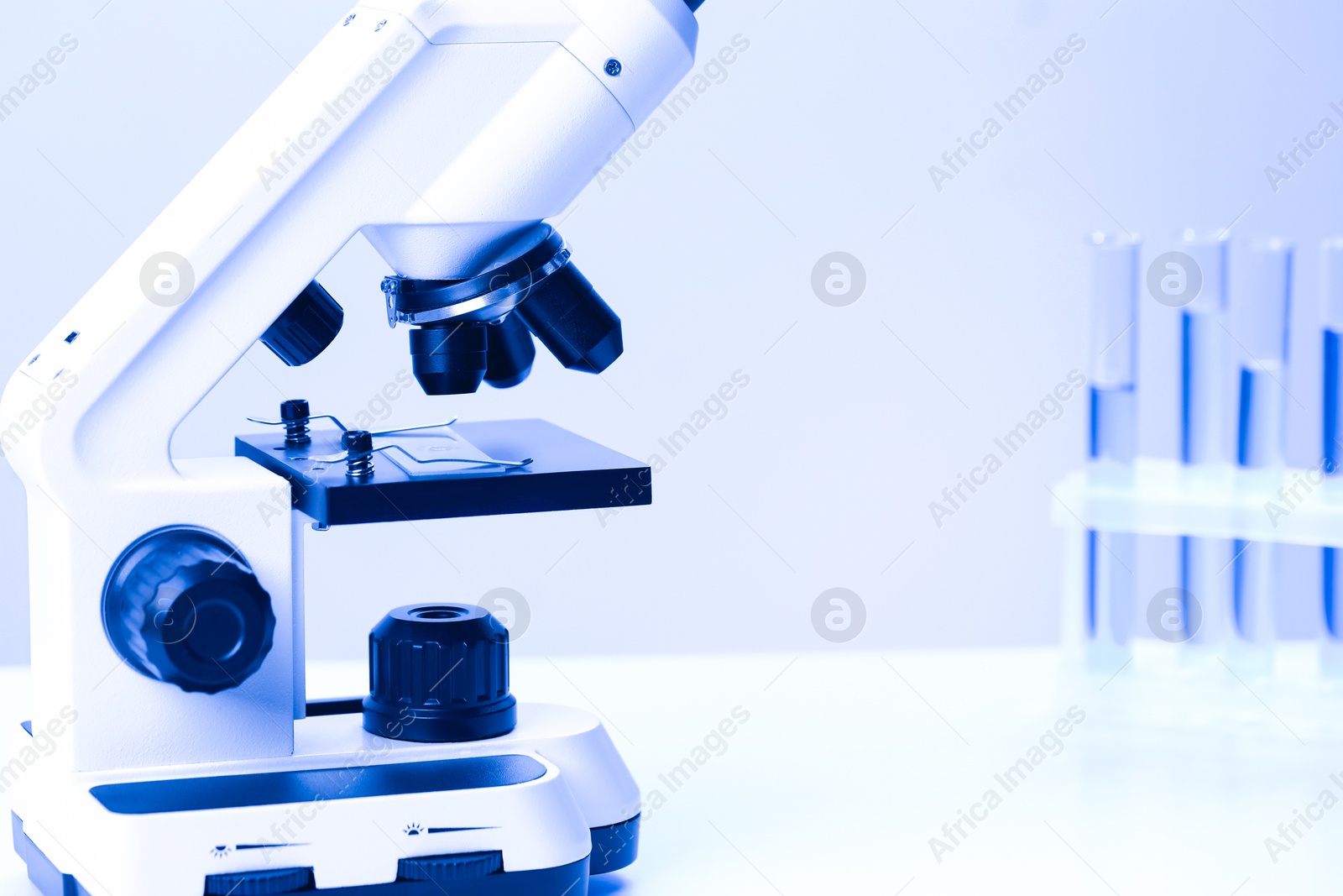 Photo of Science. Microscope with glass slide on table, closeup. Space for text