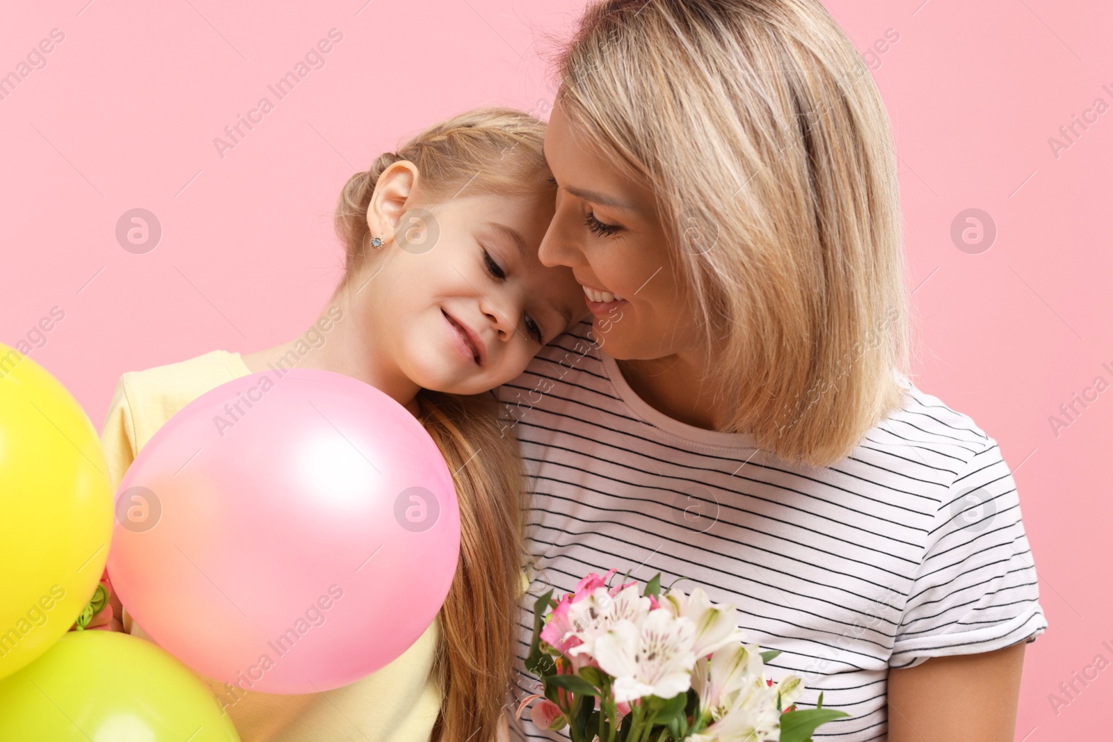 Photo of Little daughter congratulating her mom with bouquet of alstroemeria flowers and balloons on pink background. Happy Mother's Day