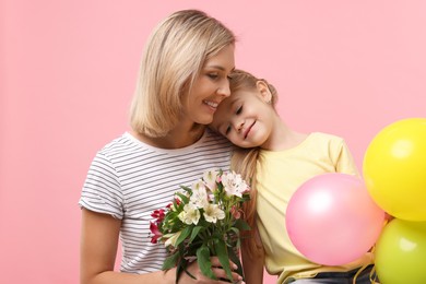 Photo of Little daughter congratulating her mom with bouquet of alstroemeria flowers and balloons on pink background. Happy Mother's Day