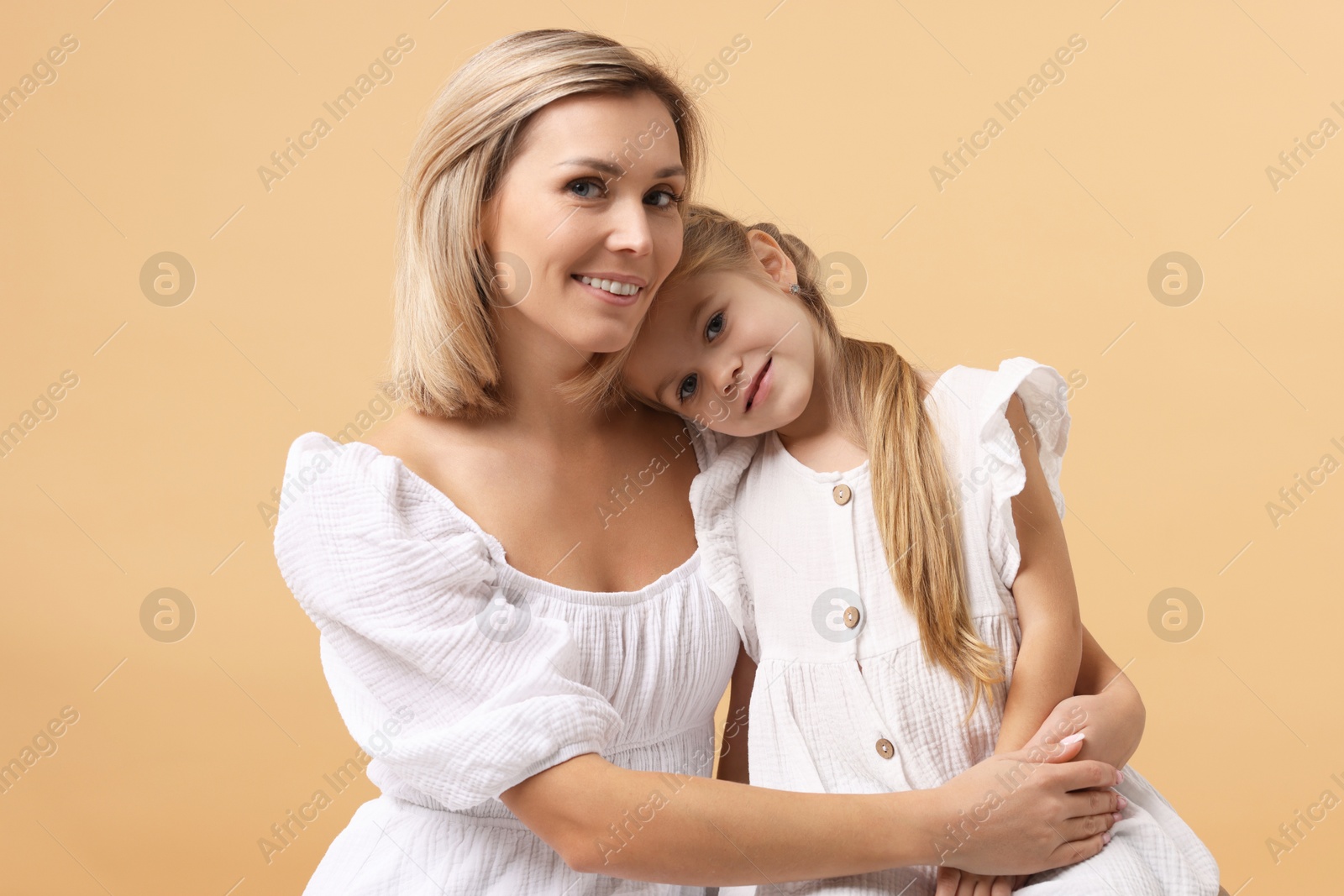 Photo of Cute little girl with her mom on beige background. Happy Mother's Day