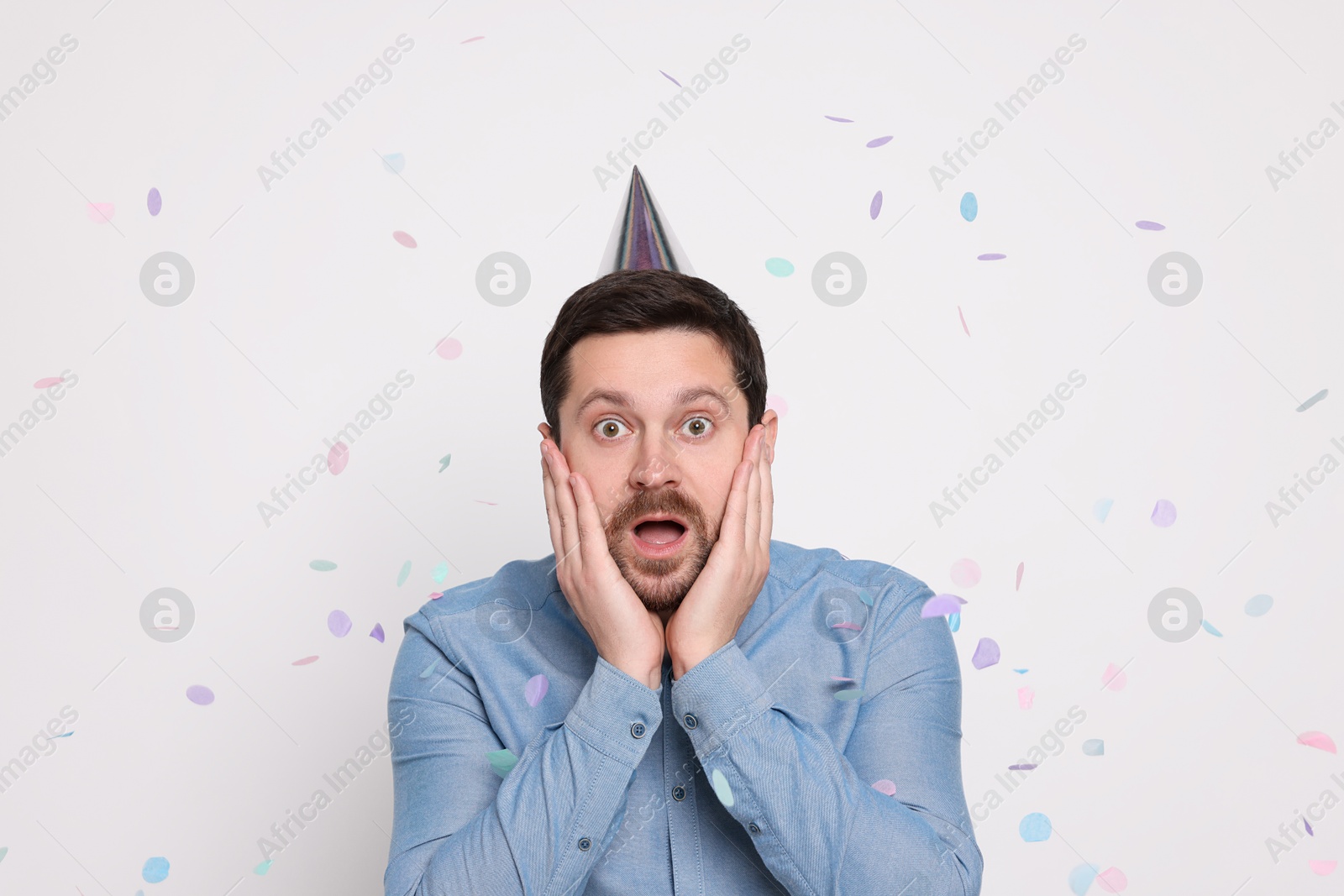 Photo of Emotional man and flying confetti on white background. Surprise party