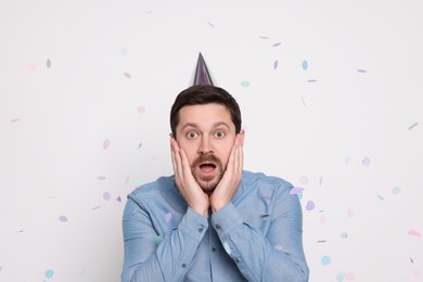 Emotional man and flying confetti on white background. Surprise party