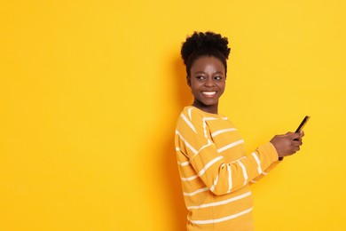 Photo of Happy woman with smartphone on yellow background. Space for text