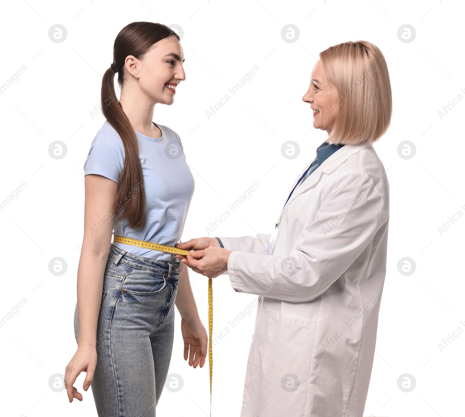 Photo of Happy woman lost weight. Nutritionist measuring patient's waist with tape on white background