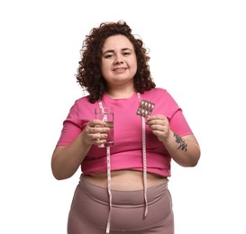 Photo of Happy plus size woman holding blister of weight loss supplements and glass of water on white background