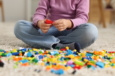 Photo of Girl playing with building blocks on floor at home, closeup