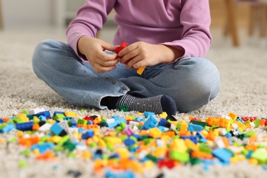 Photo of Girl playing with building blocks on floor at home, closeup