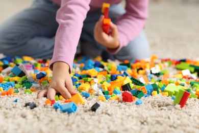 Photo of Girl playing with building blocks on floor at home, closeup