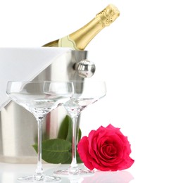 Photo of Bottle of champagne in ice bucket, beautiful rose and empty glasses isolated on white