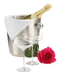 Bottle of champagne in ice bucket, beautiful rose and empty glasses isolated on white