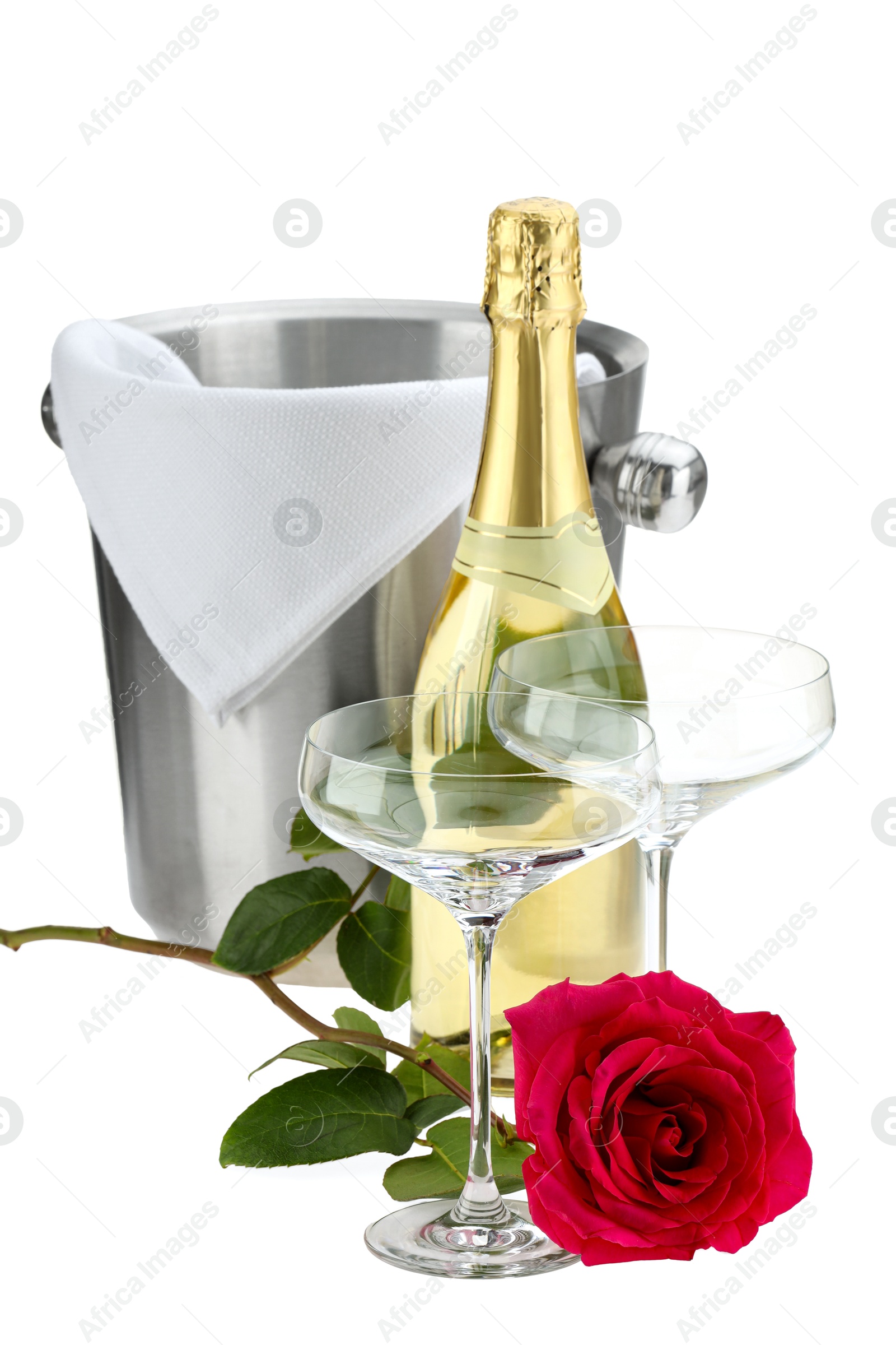 Photo of Bottle of champagne, glasses, beautiful rose and ice bucket isolated on white