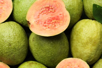 Photo of Fresh cut and whole guava fruits with water drops as background, top view