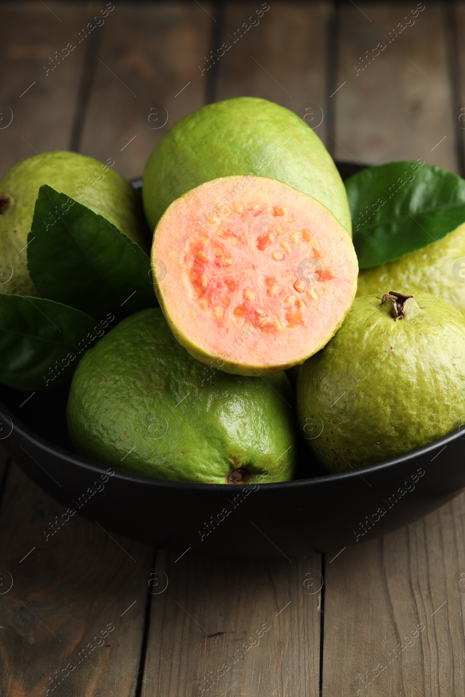 Photo of Fresh guava fruits in bowl on wooden table, closeup