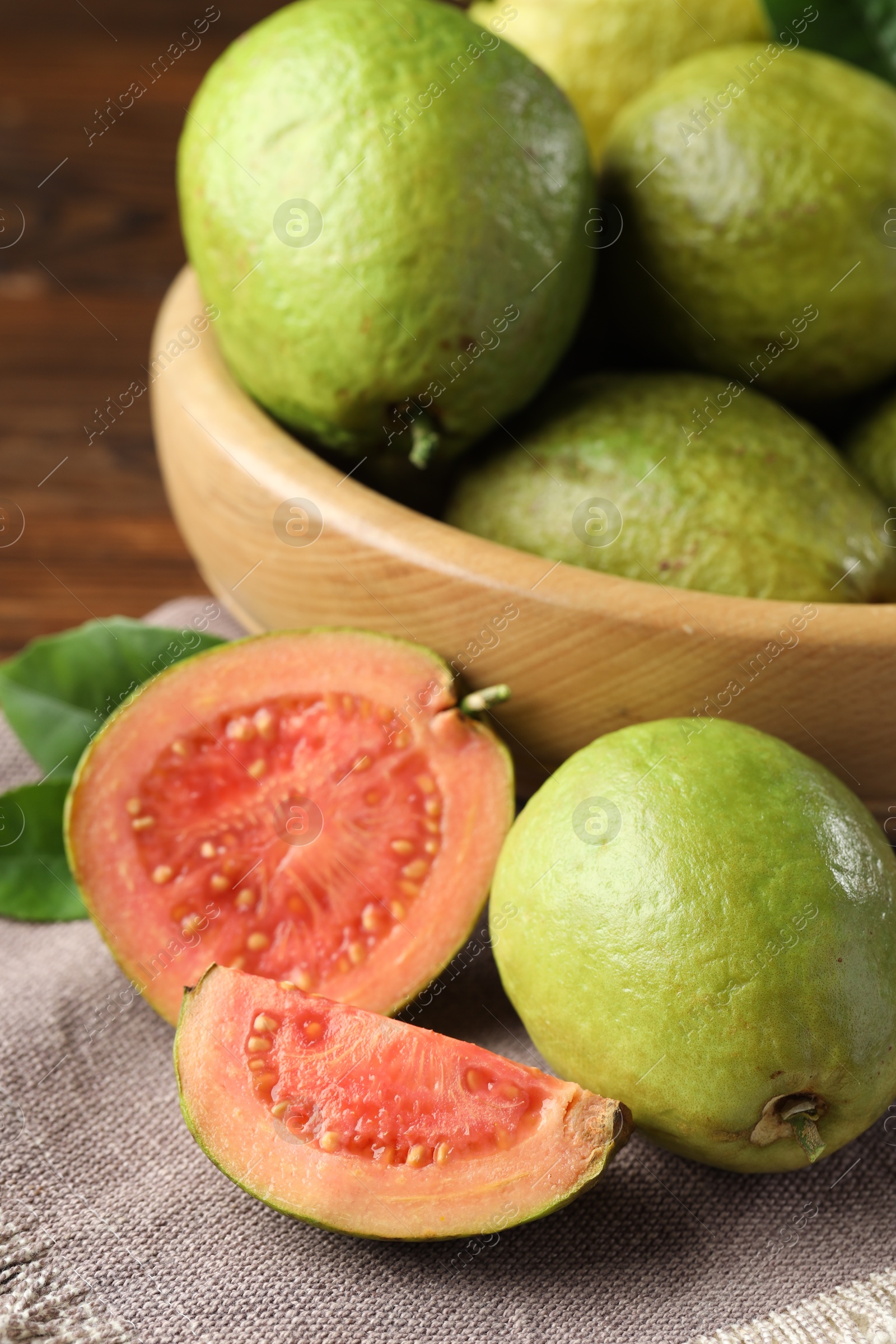 Photo of Fresh cut and whole guava fruits on table, closeup