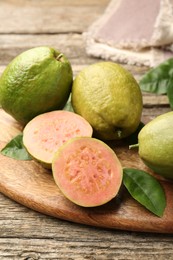 Photo of Fresh whole and cut guava fruits on wooden table, closeup