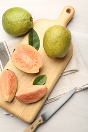 Photo of Fresh whole and cut guava fruits on white wooden table, flat lay