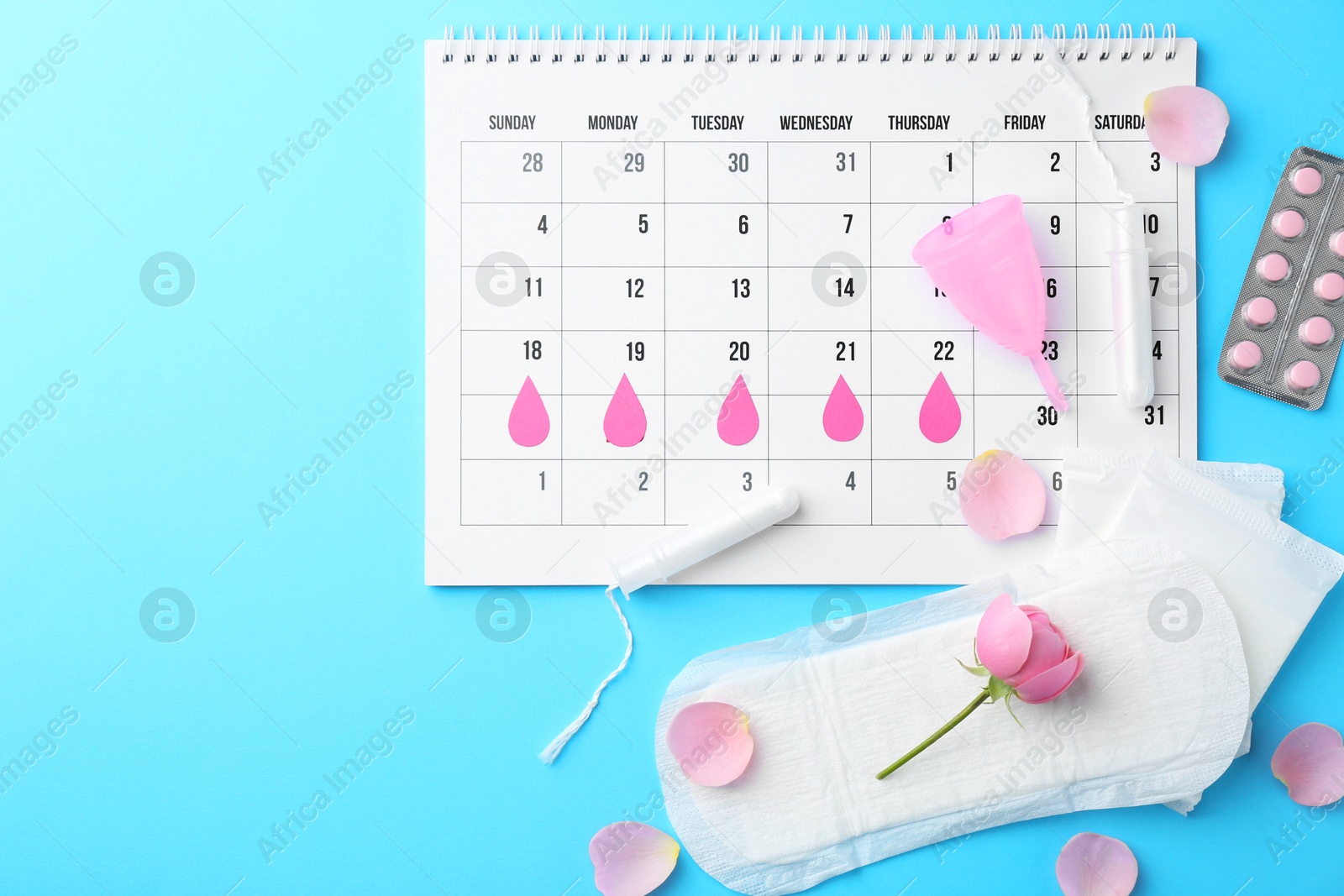 Photo of Flat lay composition with calendar and menstrual products on light blue background