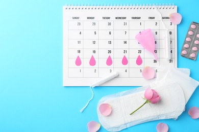 Photo of Flat lay composition with calendar and menstrual products on light blue background