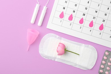 Photo of Flat lay composition with calendar and menstrual products on violet background