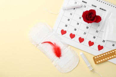 Photo of Flat lay composition with calendar and menstrual products on beige background