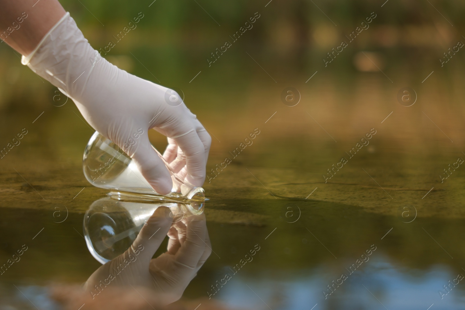 Photo of Examination of water quality. Researcher taking water sample from lake outdoors, closeup. Space for text