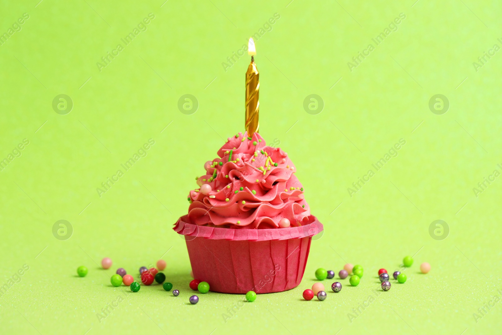 Photo of Tasty cupcake with burning candle on light green background