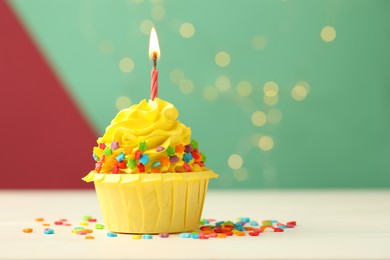 Photo of Tasty cupcake with burning candle on color background with blurred lights