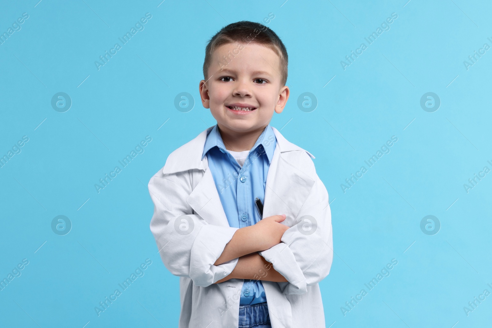 Photo of Little boy pretending to be doctor on light blue background. Dreaming of future profession