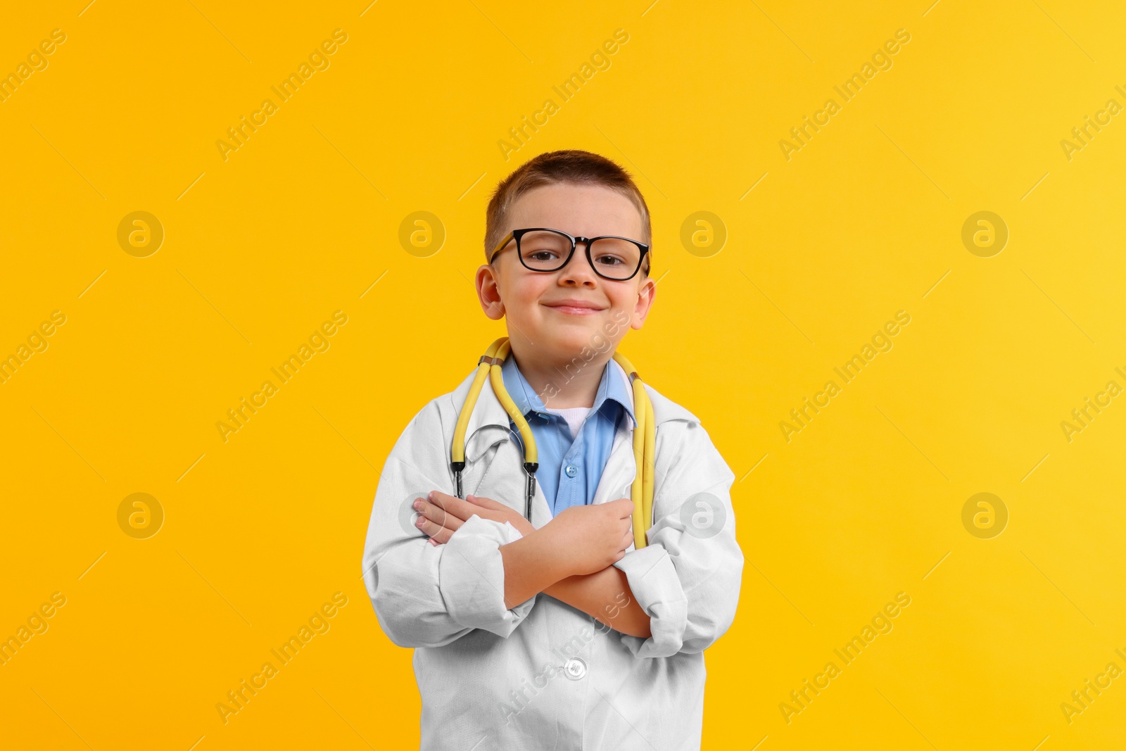 Photo of Little boy with stethoscope pretending to be doctor on yellow background. Dreaming of future profession