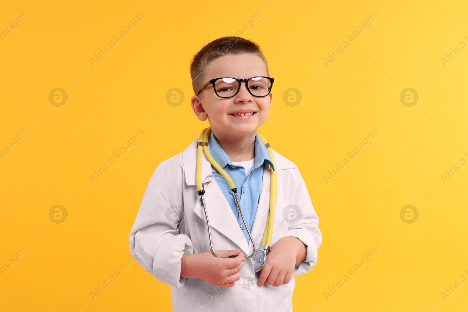 Photo of Little boy with stethoscope pretending to be doctor on yellow background. Dreaming of future profession