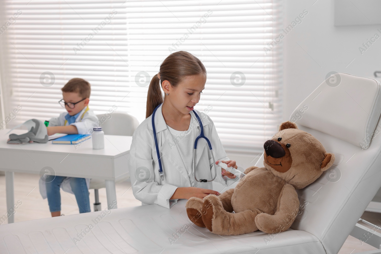 Photo of Little boy and girl with toy pretending to be doctors indoors